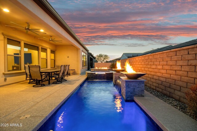 644 E Las Puertas Ln, Queen Creek, AZ 85140 - pool at dusk with ceiling fan, a pool with connected hot tub, a patio, and fence