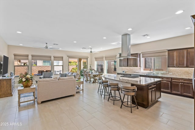 644 E Las Puertas Ln, Queen Creek, AZ 85140 - kitchen with visible vents, ceiling fan, island exhaust hood, backsplash, and a breakfast bar area