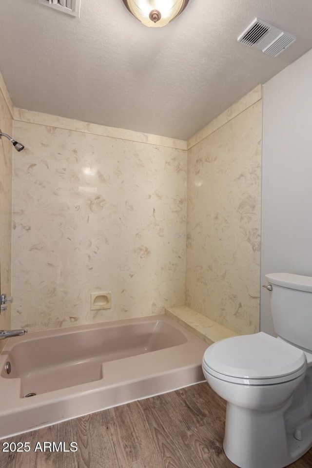 bathroom with wood finished floors, toilet, a tub to relax in, and a shower