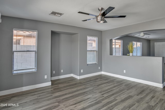 empty room with visible vents, baseboards, ceiling fan, and wood finished floors