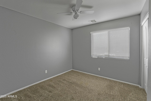 unfurnished room with visible vents, a healthy amount of sunlight, carpet, and a ceiling fan