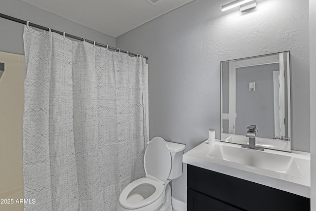 full bath featuring vanity, curtained shower, toilet, and a textured wall