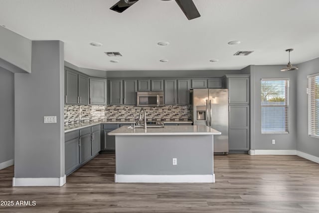 kitchen with stainless steel appliances, backsplash, gray cabinetry, and visible vents