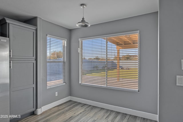 unfurnished dining area featuring baseboards and light wood finished floors