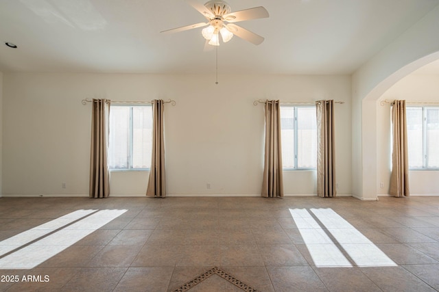 tiled empty room with ceiling fan and a healthy amount of sunlight