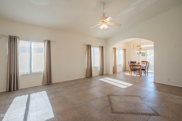 tiled spare room with ceiling fan with notable chandelier