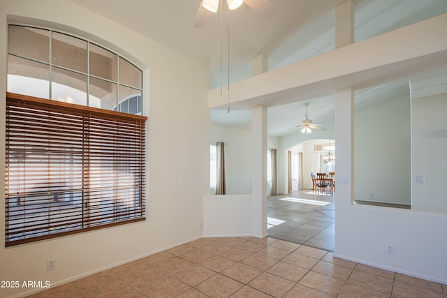 empty room with light tile patterned floors, vaulted ceiling, and ceiling fan