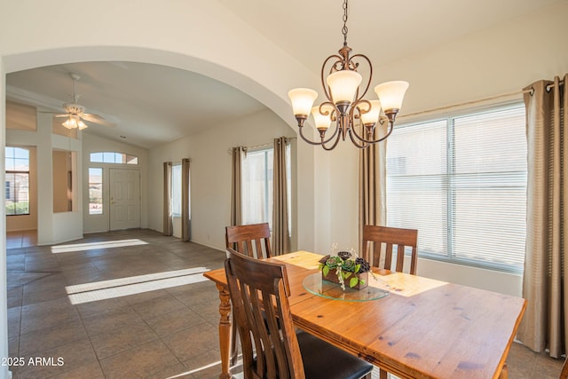 dining space featuring ceiling fan with notable chandelier, vaulted ceiling, and dark tile patterned floors