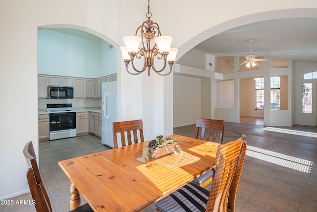 tiled dining space with ceiling fan with notable chandelier and high vaulted ceiling