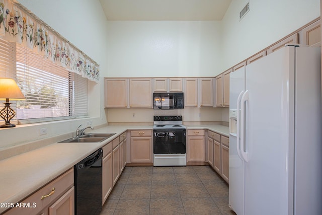 kitchen with light brown cabinetry, sink, and black appliances