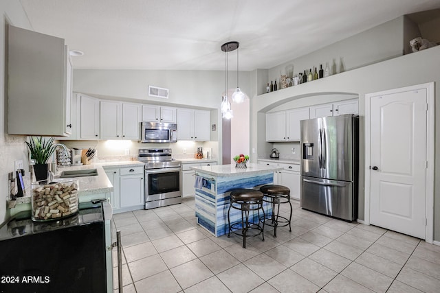 kitchen with appliances with stainless steel finishes, hanging light fixtures, sink, white cabinets, and a center island