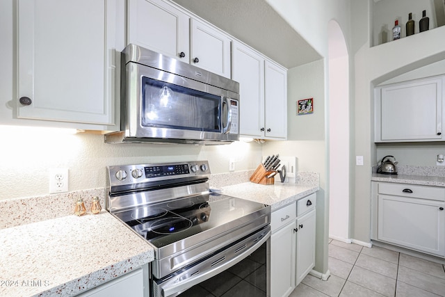 kitchen featuring white cabinetry, light tile patterned floors, light stone countertops, and stainless steel appliances