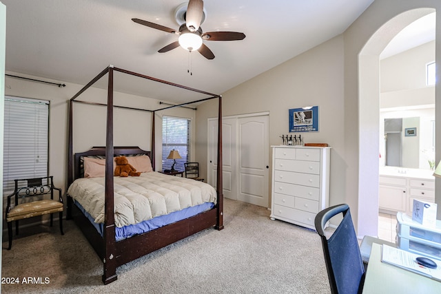 bedroom featuring ensuite bath, lofted ceiling, light carpet, ceiling fan, and a closet