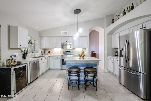 kitchen with a kitchen island, appliances with stainless steel finishes, decorative light fixtures, a kitchen breakfast bar, and lofted ceiling