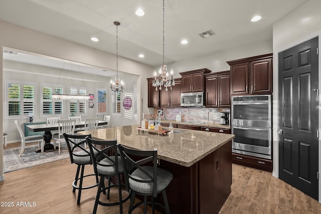 27276 N 81st Ln, Peoria, AZ 85383 - kitchen featuring appliances with stainless steel finishes, a chandelier, a sink, tasteful backsplash, and a breakfast bar area