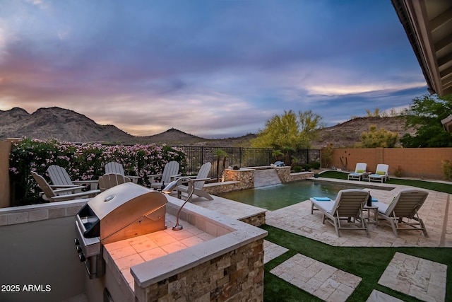 27276 N 81st Ln, Peoria, AZ 85383 - patio terrace at dusk featuring a fenced backyard, a mountain view, and area for grilling