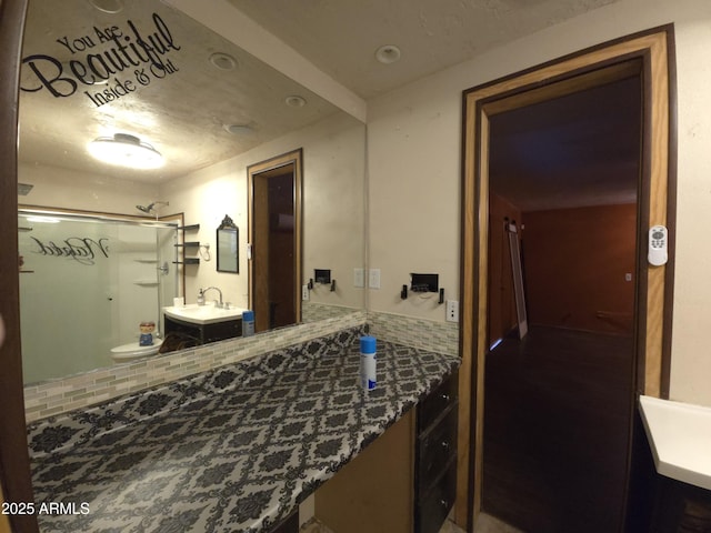 bathroom featuring decorative backsplash, a shower with door, and vanity