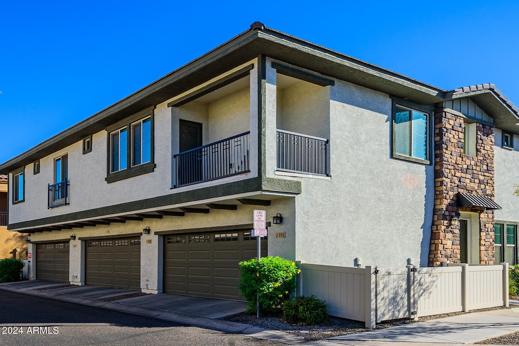 view of side of property featuring a garage and a balcony