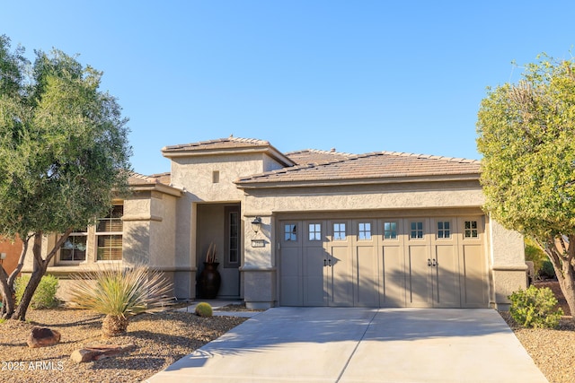 prairie-style home with a tile roof, a garage, driveway, and stucco siding