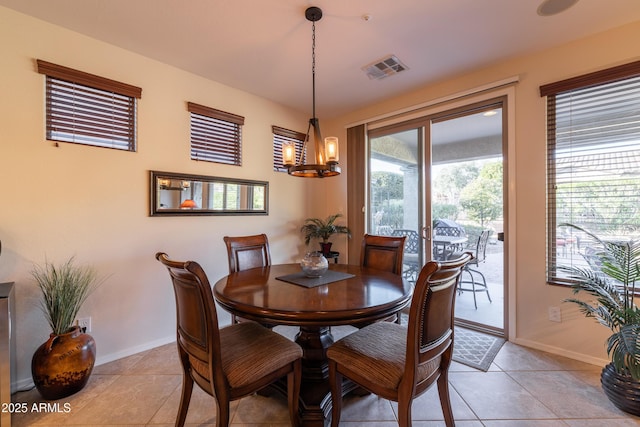 dining area with light tile patterned flooring, baseboards, visible vents, and a chandelier