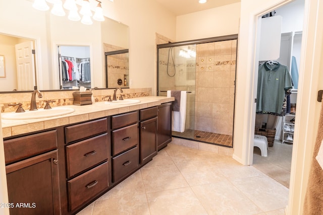 full bath with tile patterned flooring, a shower stall, a walk in closet, and a sink