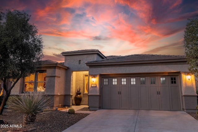 prairie-style house featuring stucco siding, an attached garage, and concrete driveway