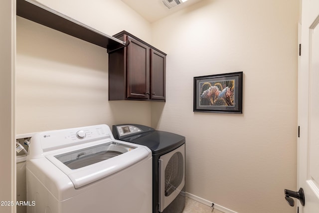 laundry area featuring washer and clothes dryer, visible vents, cabinet space, and baseboards