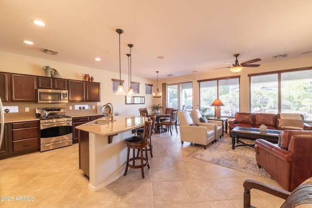 kitchen featuring open floor plan, stainless steel appliances, visible vents, and a sink