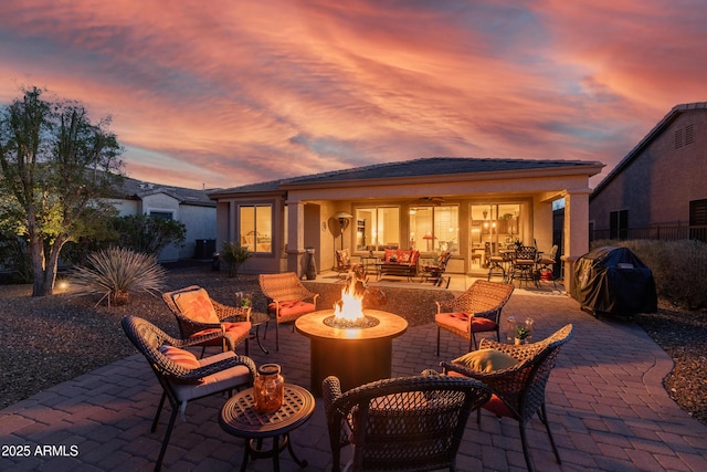 patio terrace at dusk featuring a fire pit and a grill