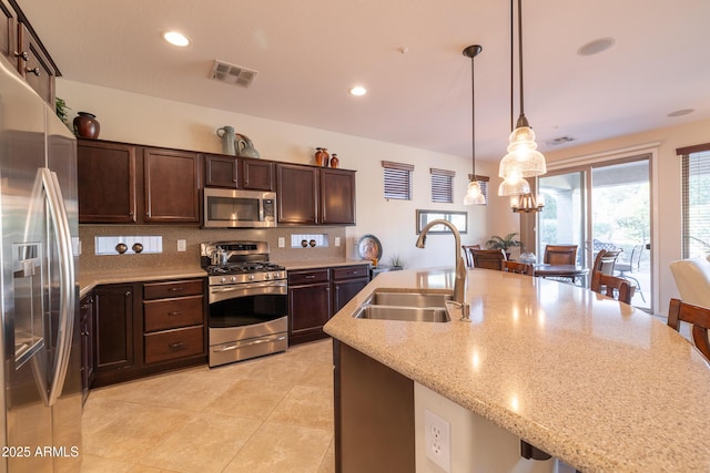 kitchen featuring visible vents, a sink, decorative light fixtures, dark brown cabinetry, and appliances with stainless steel finishes