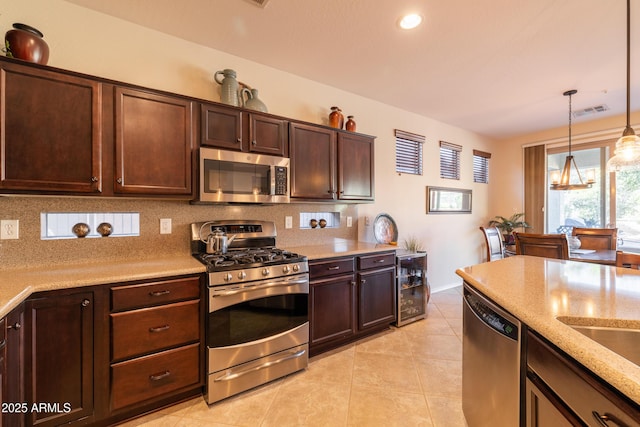 kitchen with backsplash, light stone countertops, dark brown cabinetry, light tile patterned floors, and appliances with stainless steel finishes