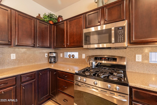 kitchen featuring light stone counters, stainless steel appliances, and backsplash