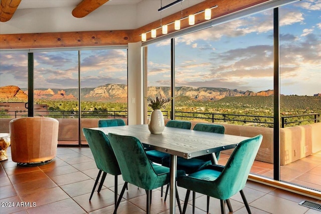 sunroom / solarium featuring a healthy amount of sunlight, a mountain view, beam ceiling, and ceiling fan