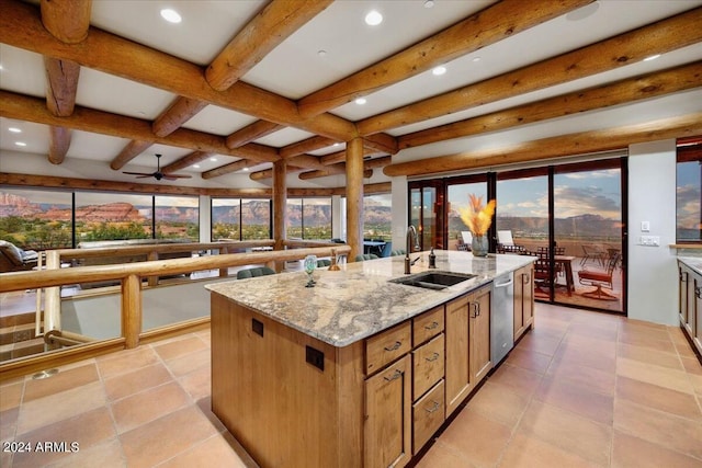 kitchen with sink, a kitchen island with sink, beam ceiling, light stone counters, and stainless steel dishwasher