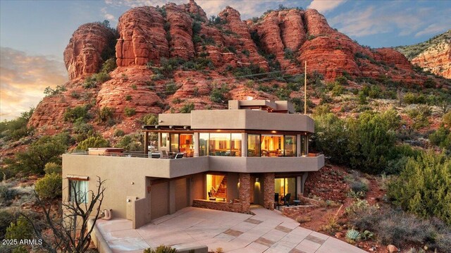 back house at dusk with a patio area, a pergola, an outdoor fire pit, and a hot tub