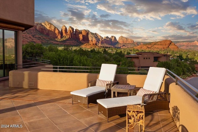 patio terrace at dusk with a mountain view and a balcony