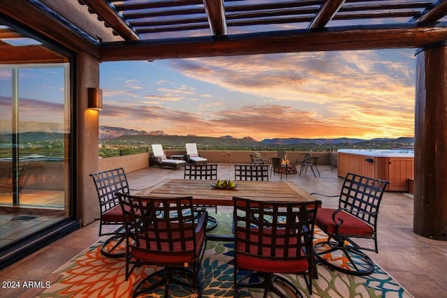 patio terrace at dusk featuring a mountain view, a pergola, and a hot tub