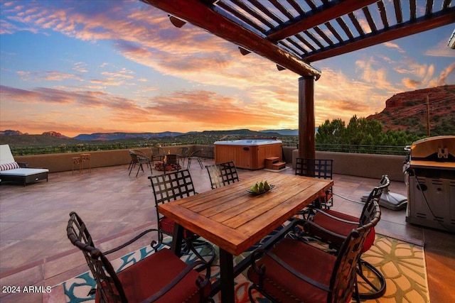 patio terrace at dusk featuring a mountain view, a pergola, and a hot tub