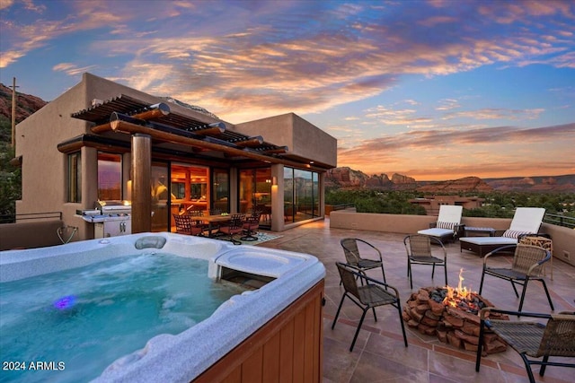 patio terrace at dusk featuring a hot tub