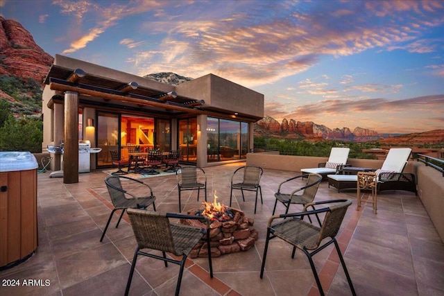 patio terrace at dusk featuring a mountain view and a fire pit