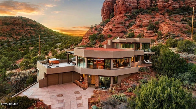 back house at dusk with a mountain view and a balcony