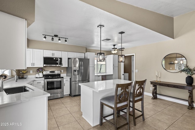 6605 W Altadena Ave, Glendale, AZ 85304 - kitchen with appliances with stainless steel finishes, a ceiling fan, light tile patterned floors, and a breakfast bar