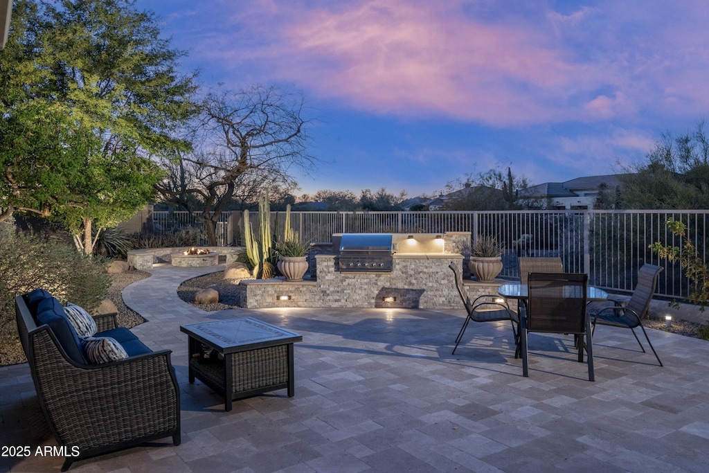 patio terrace at dusk with area for grilling and a fire pit