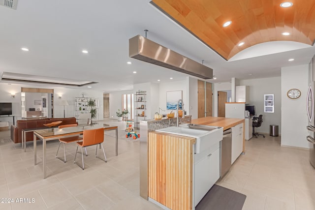 kitchen featuring white cabinetry, dishwasher, sink, an island with sink, and vaulted ceiling