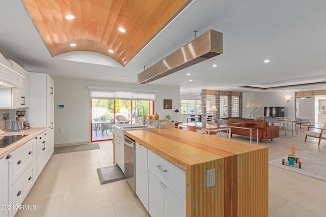 kitchen with lofted ceiling, black electric stovetop, stainless steel dishwasher, a large island, and white cabinetry