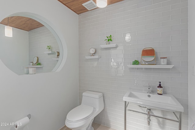 bathroom featuring sink, tile walls, and toilet