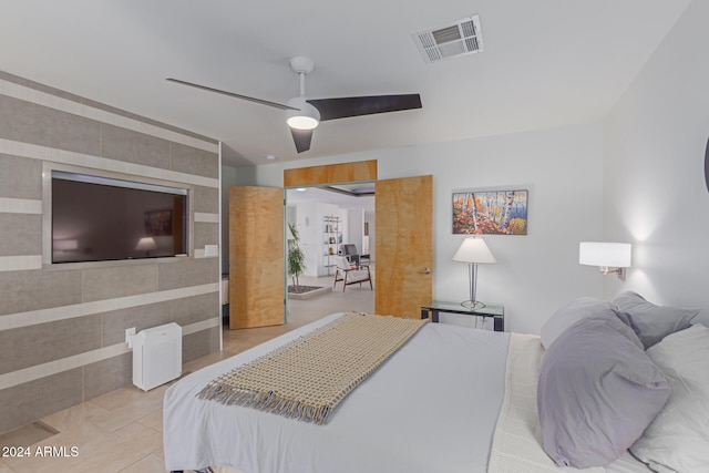 bedroom with ceiling fan, light tile patterned floors, and tile walls