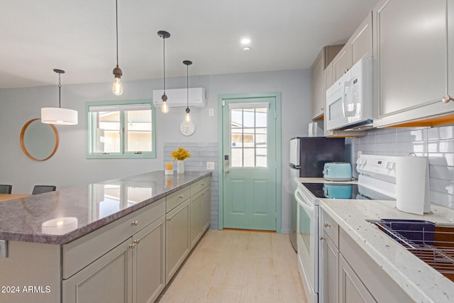 kitchen featuring a healthy amount of sunlight, white appliances, hanging light fixtures, and a wall mounted AC