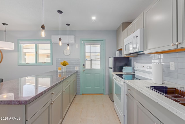 kitchen with hanging light fixtures, white appliances, a wall mounted air conditioner, and a wealth of natural light