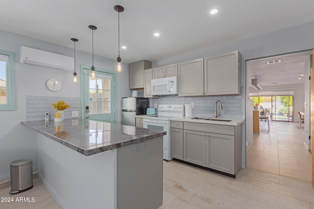 kitchen featuring white appliances, hanging light fixtures, sink, kitchen peninsula, and a wall unit AC